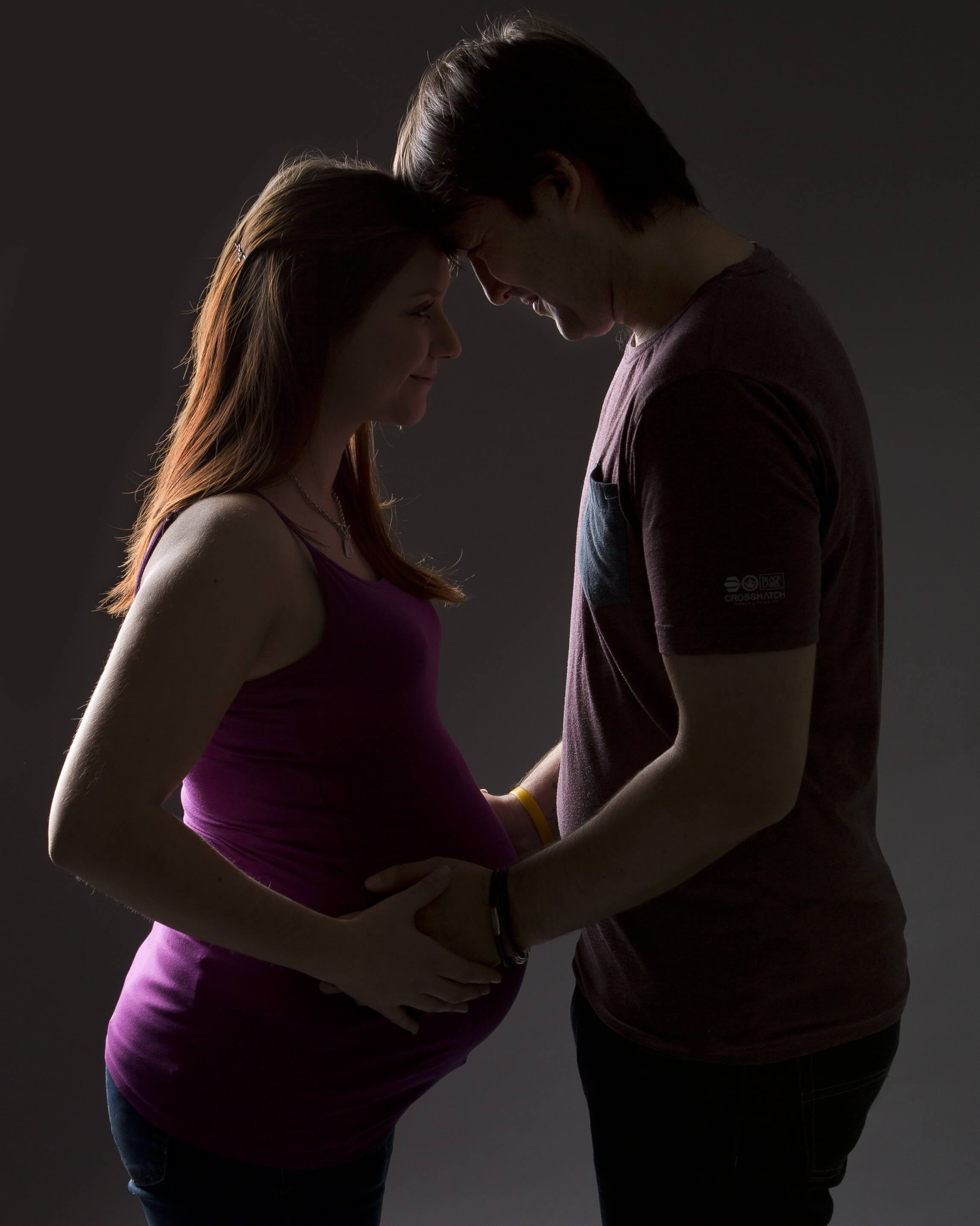 couple standing head to head for maternity photo shoot in Winchester, Hampshire