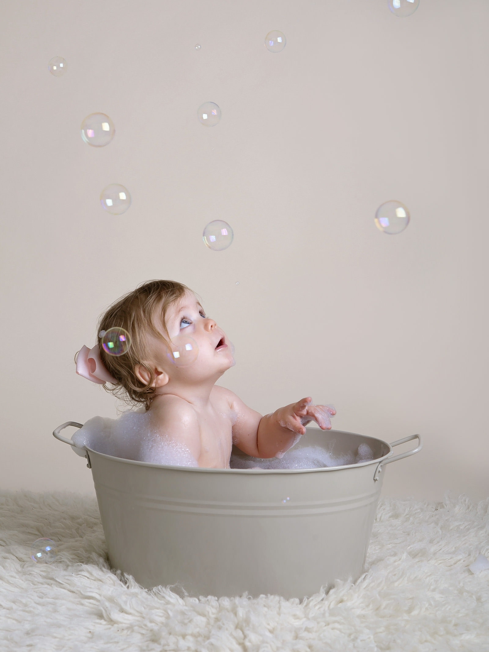 girl looking up at bubbles in tin bath by cake smash photographer Winchester