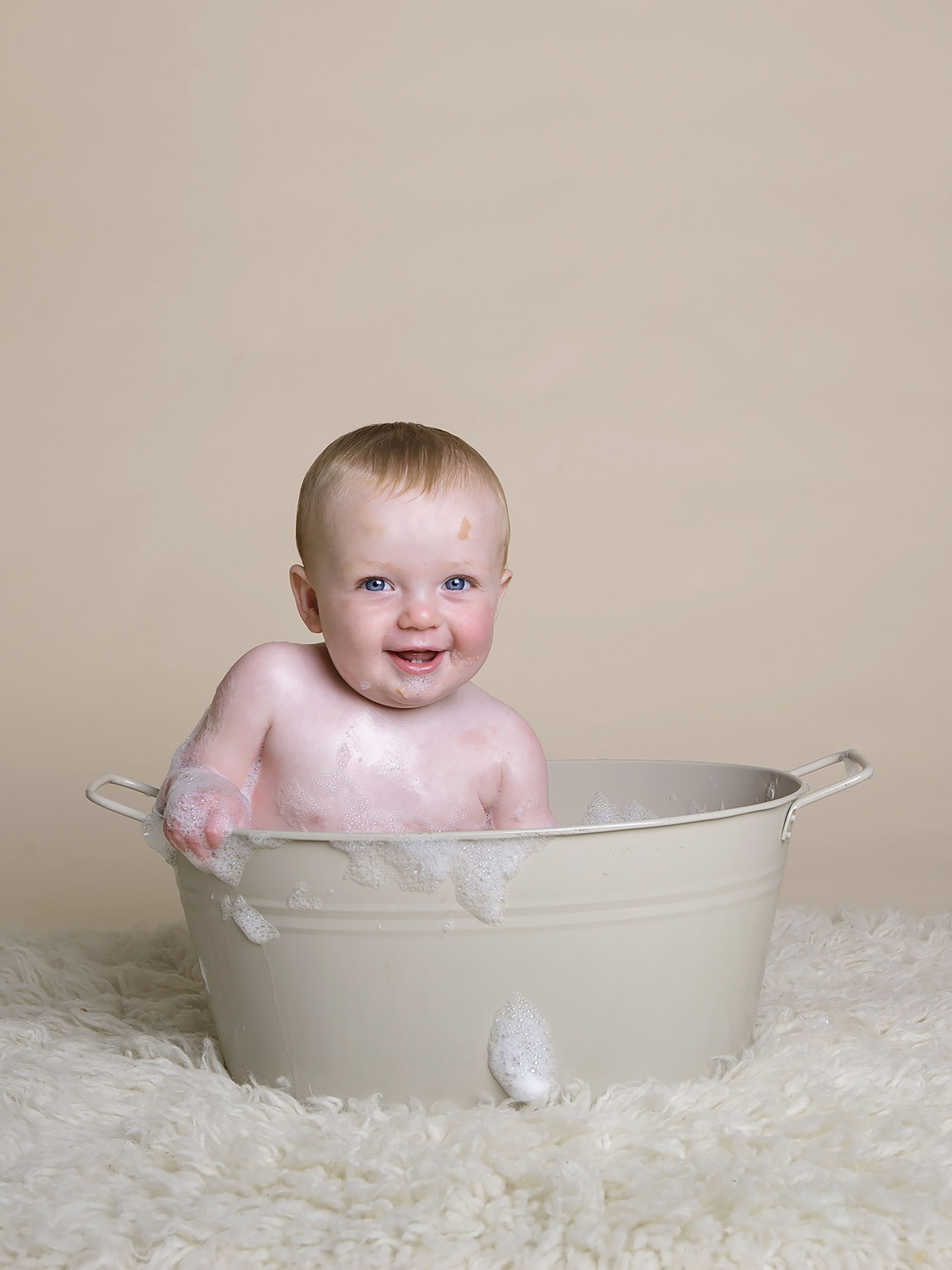 baby laughing in bath by cake smash photographer Winchester