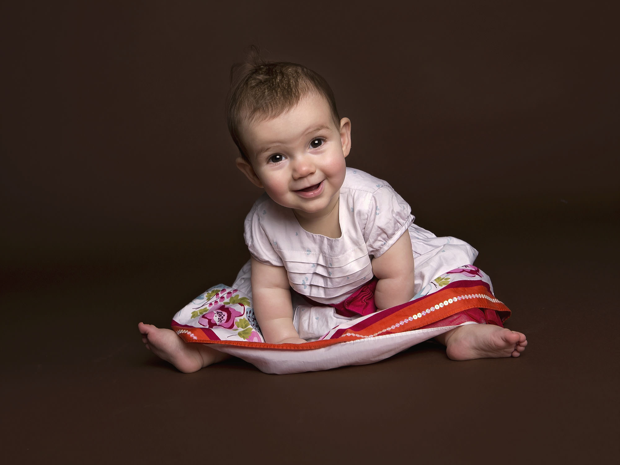 happy baby girl on dark brown backdrop by baby photographer Winchester