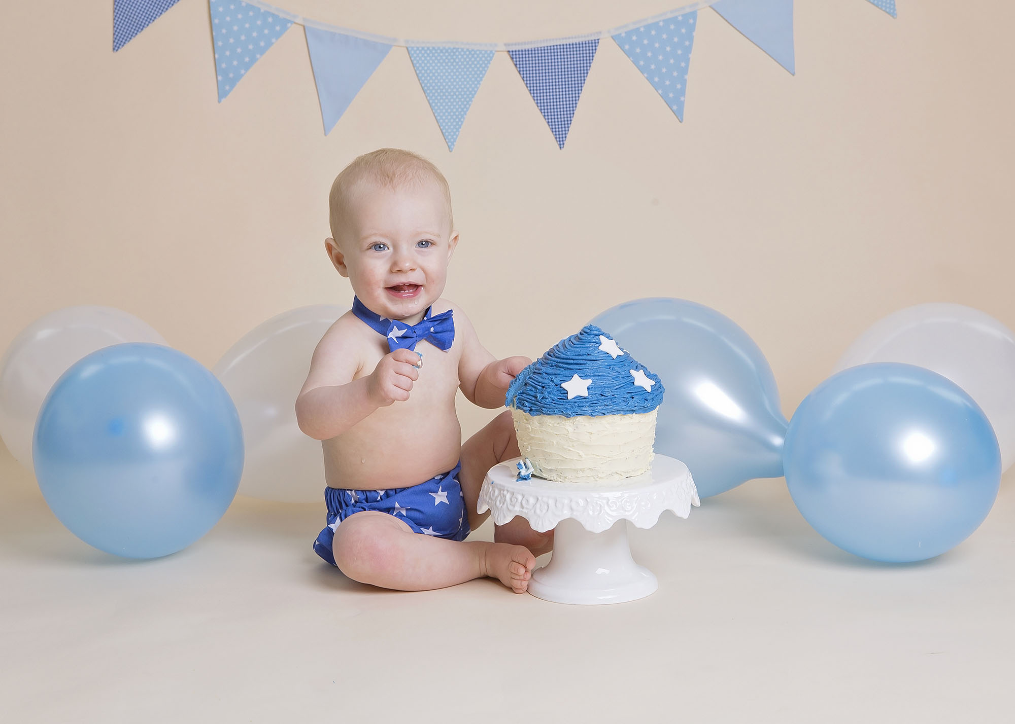 little boy with blue cake and balloons by cake smash photographer Winchester