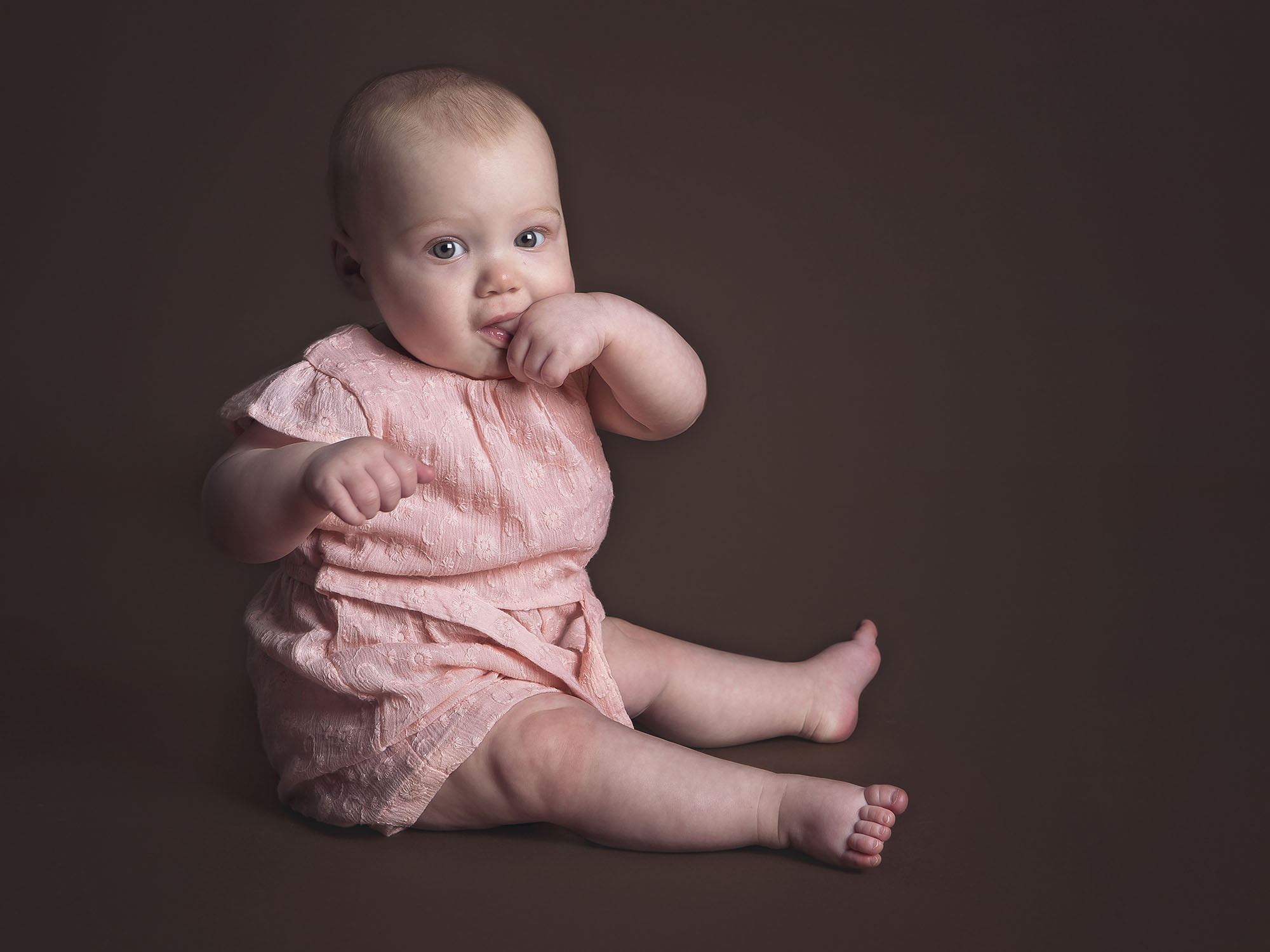 baby sitting sucking thumb by baby photographer Hampshire