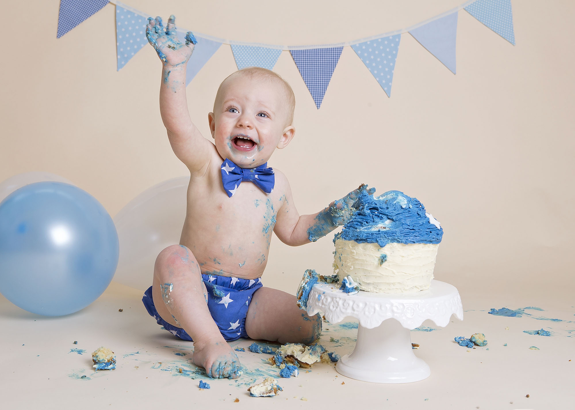 boy with blue cake, balloons and bunting by cake smash photographer Winchester