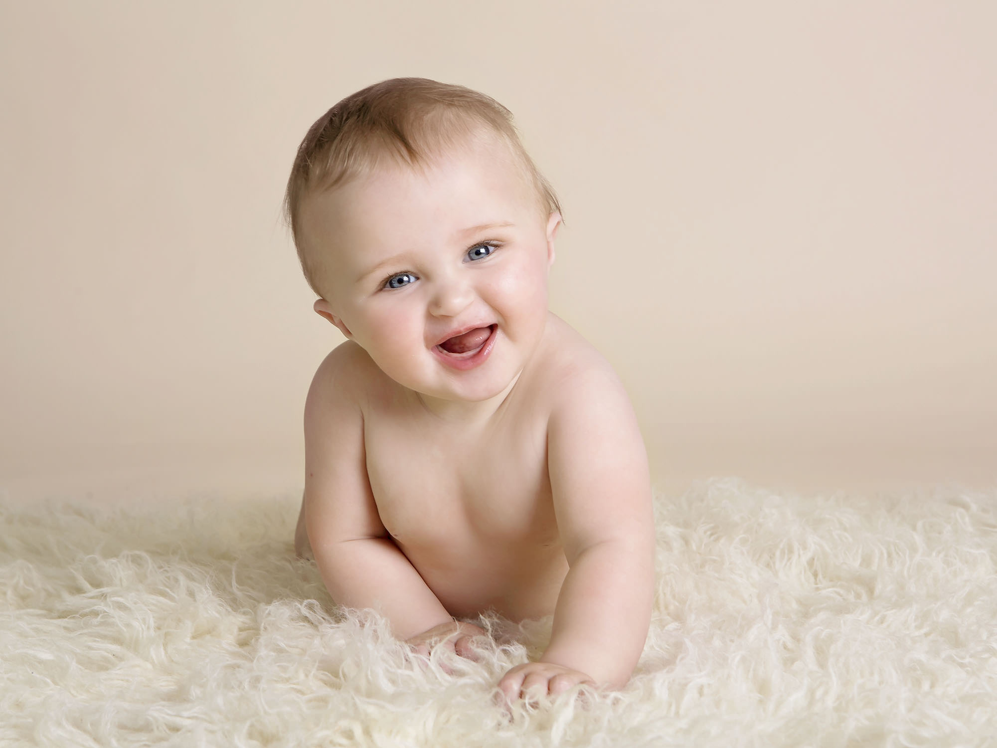 baby on fluffy rug crawling towards camera by baby photographer Winchester