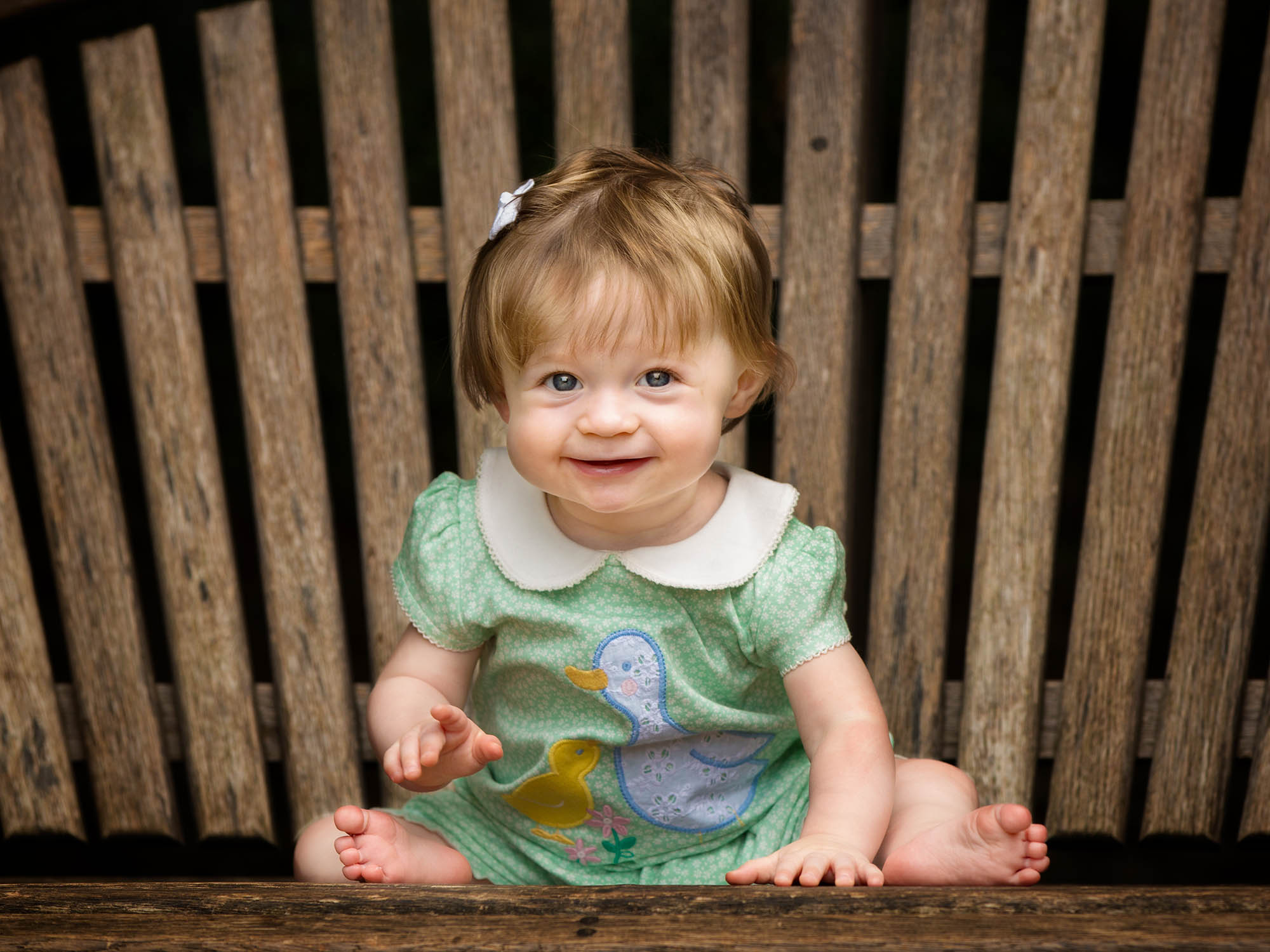 little girl in green dress on wooden bench by family photographer Winchester Hampshire 