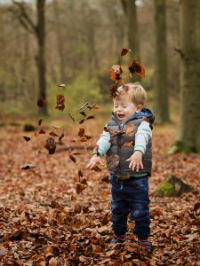 boy throwing autumn leaves in Winchester, Hampshire
