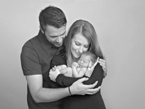 parents cuddling they new baby by newborn photographer Winchester