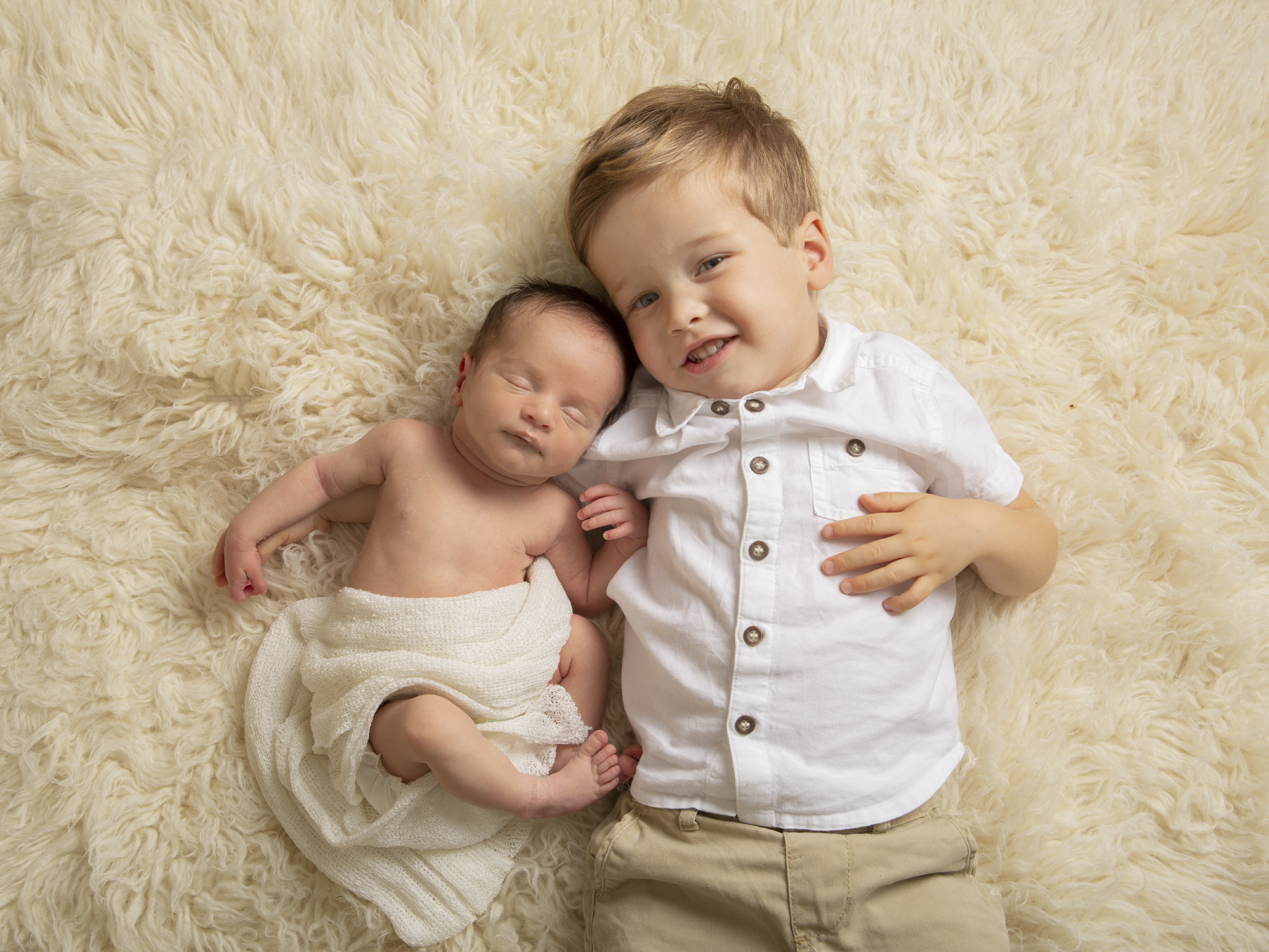 boy and new baby brother on fluffy rug by Winchester newborn photographer