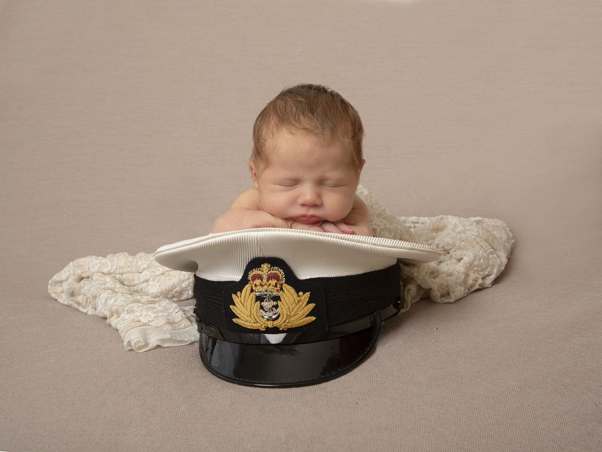 baby posed on Royal Navy hat by newborn photographer Hampshire