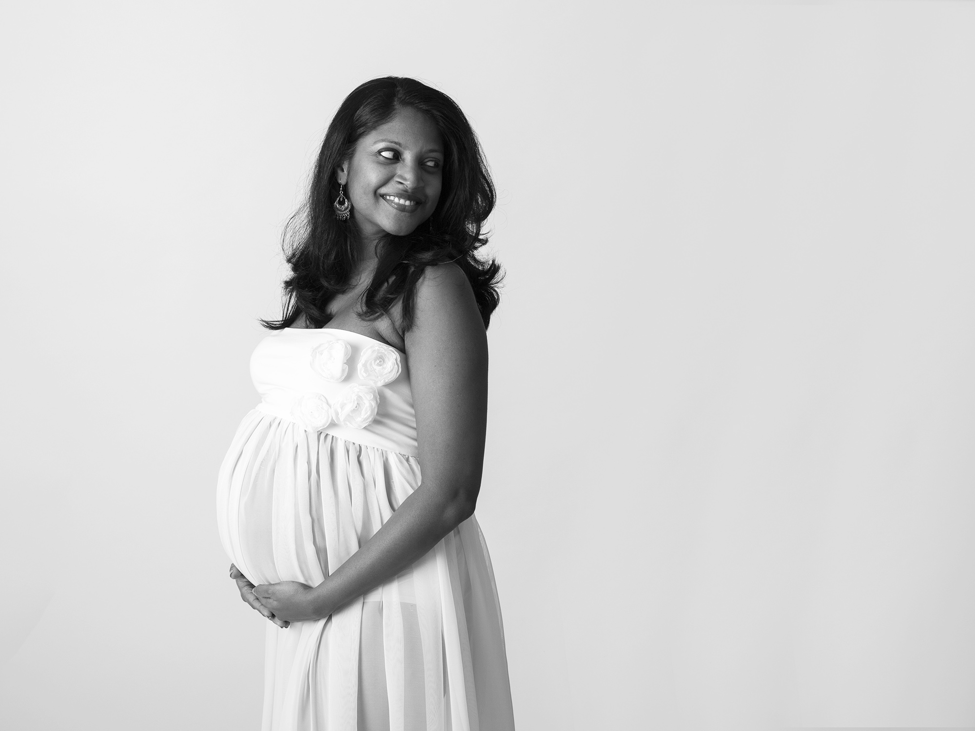 pregnant woman in flowing white dress by maternity photographer Hampshire